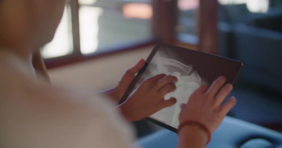 A person holds a tablet showing an x ray to another person