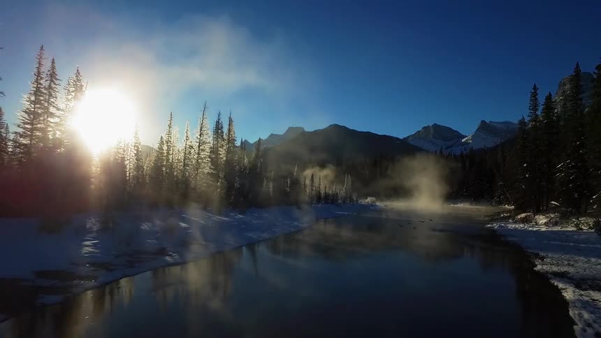 Aerial view moving down a cold river at sunset