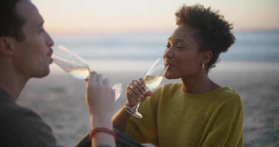A man and woman smiling and drinking at the beach