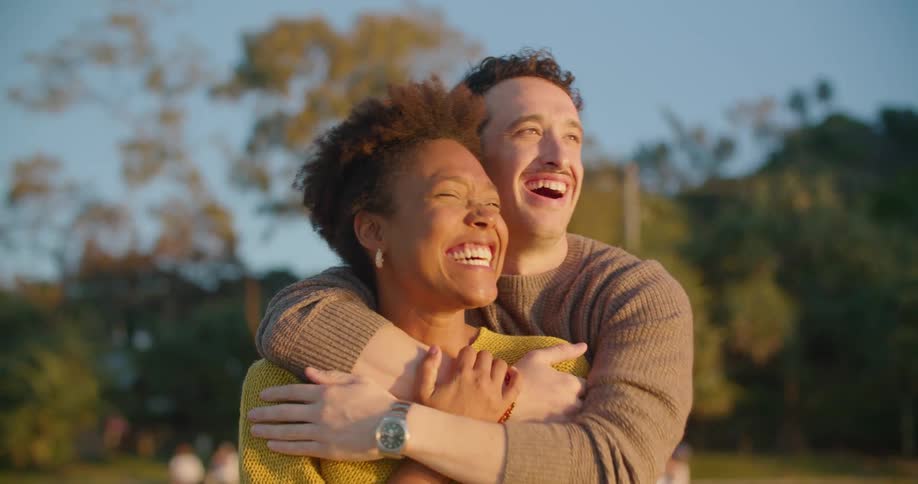 Young happy couple hugging and laughing while looking at the sunset