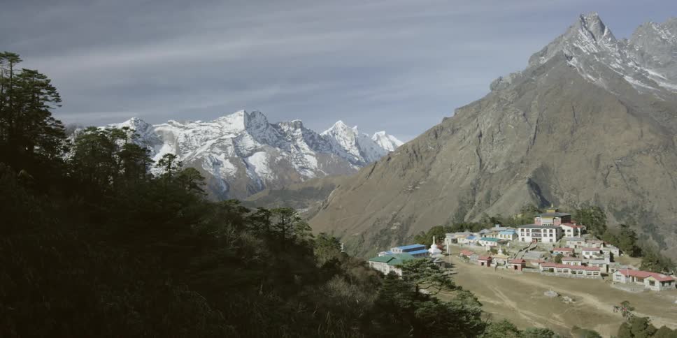 A close up view of a flag with mountains and a small village in the background