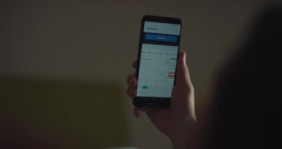 A person in a room looking at a smart phone with a wall and doorway in the background
