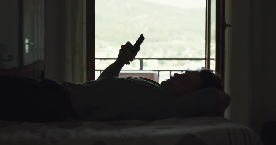 A man is laying down in front of a window pumping his fist in the air