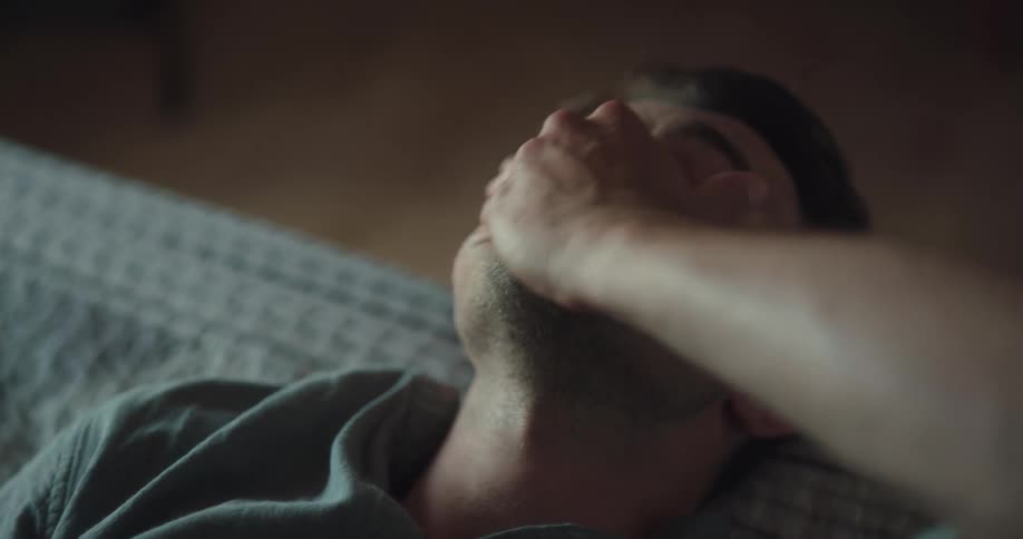 A man is laying down on a bed indoors