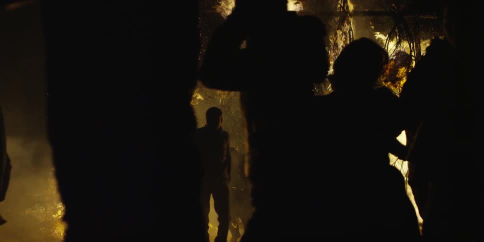 People run from a wooden area that is in flames at night