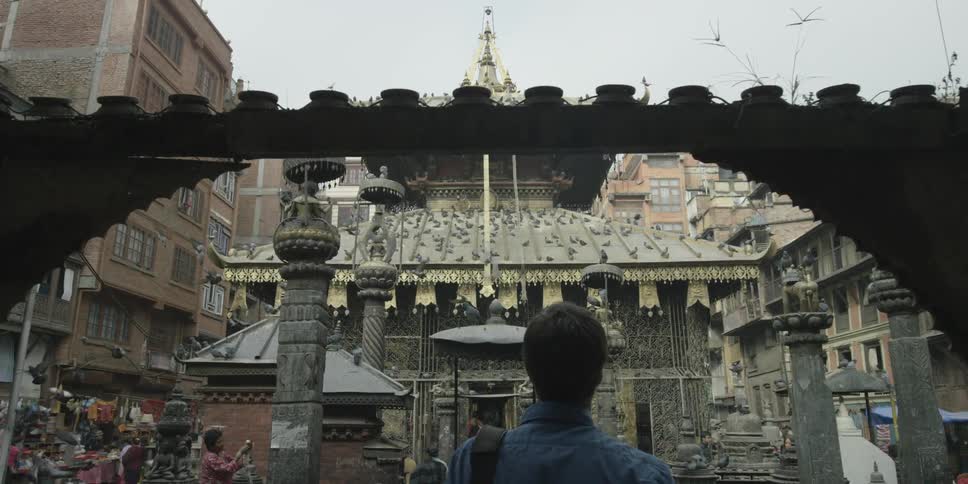 A man walks into a square with birds flying all over