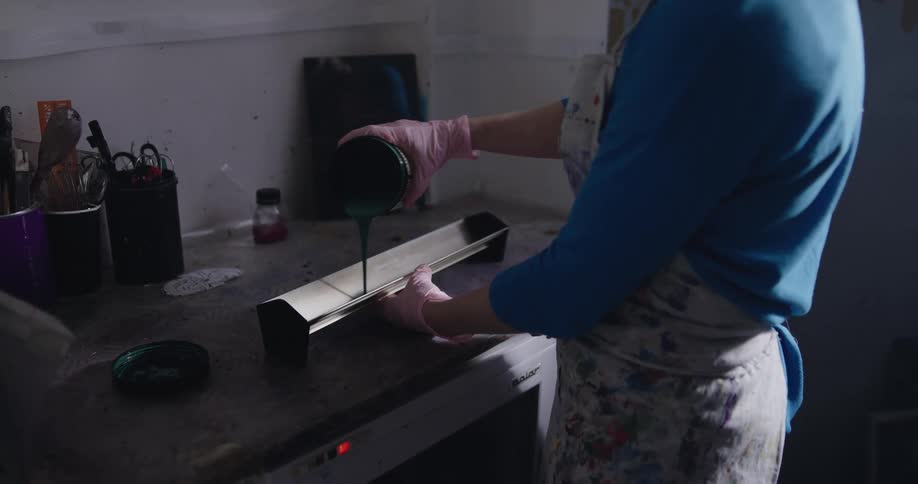 A person is pouring paint onto a machine in a dark room