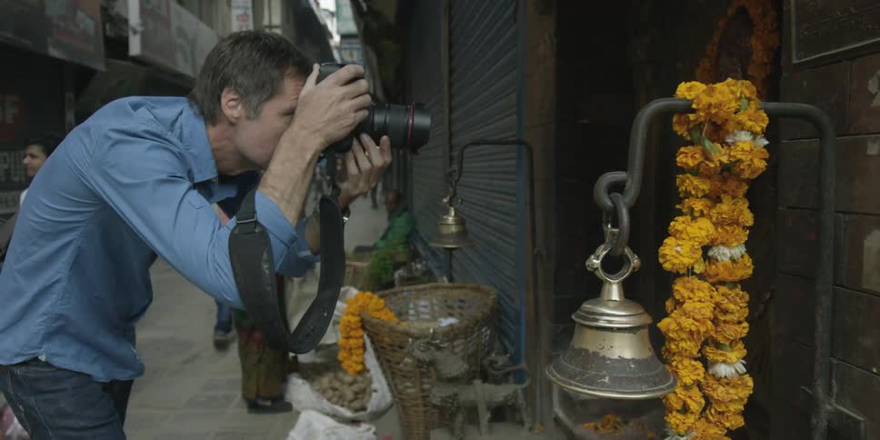 A man photographs the side of a building in an alley