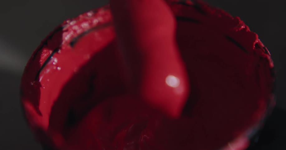 Red paint in a can being stirred