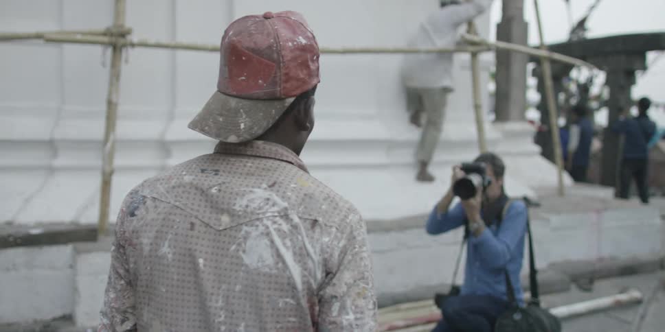 A photographer takes a picture of a man covered in splotches of pain