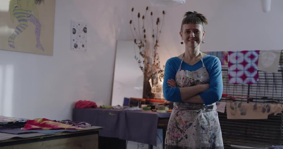 A woman is standing in a room filled with different crafting media spread on tables and displays