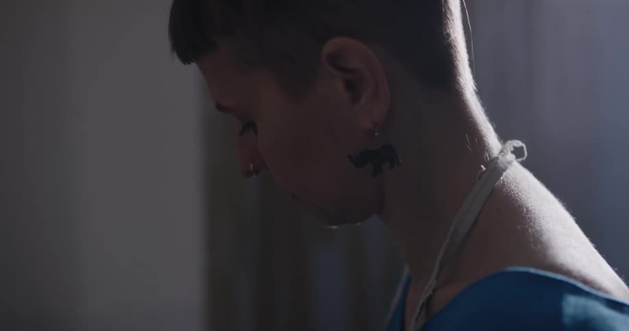 A woman stands in profile looking down at what she is doing