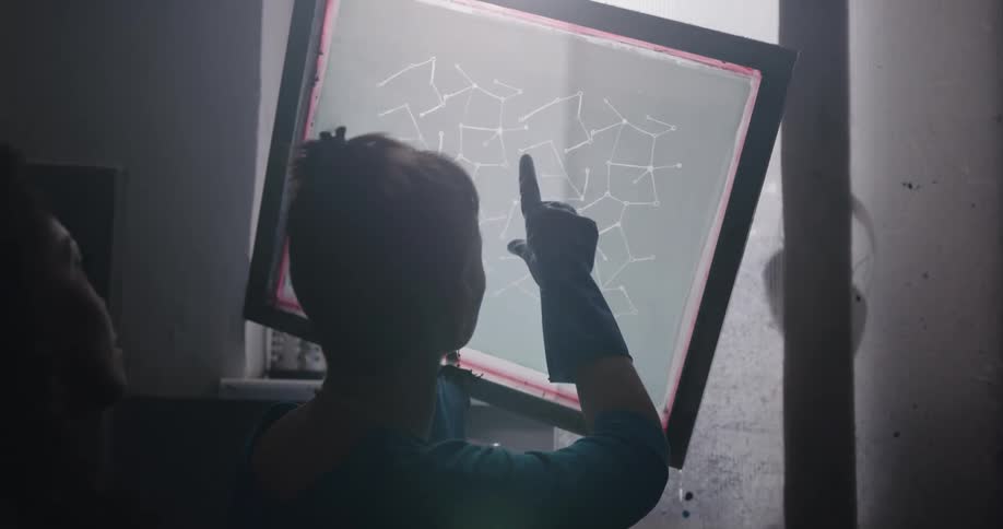 A woman lifts a glass frame under the light