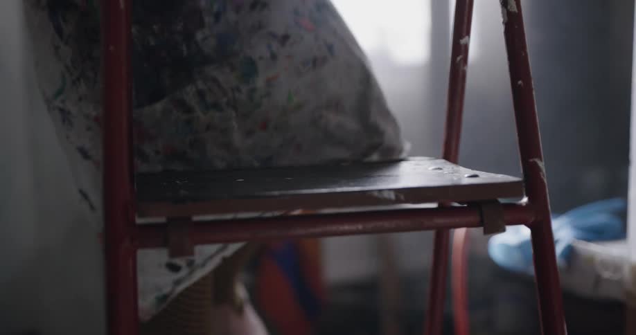 A woman steps down off a step stool in a room of a house