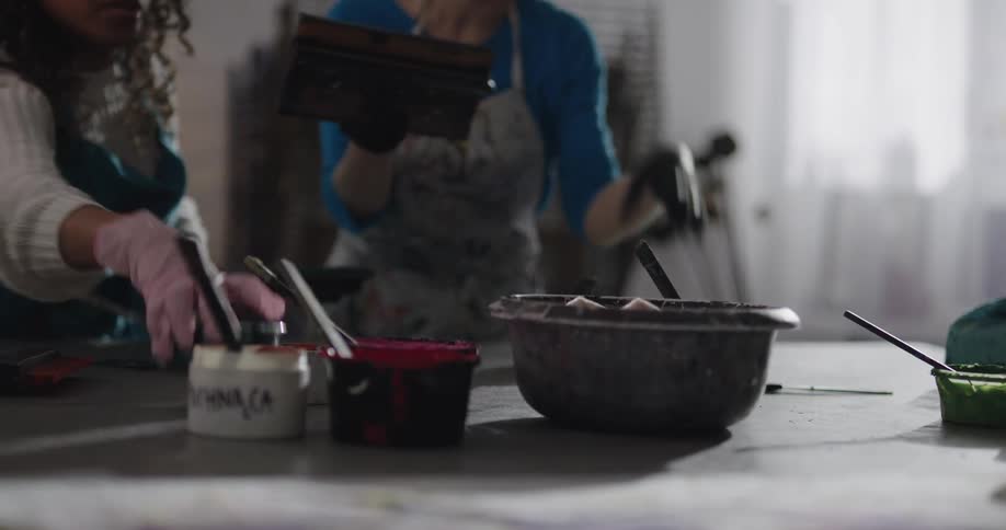 Two women are painting indoors during the day