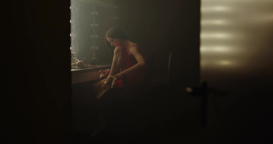 A woman is sitting by a mirror and putting on shoes