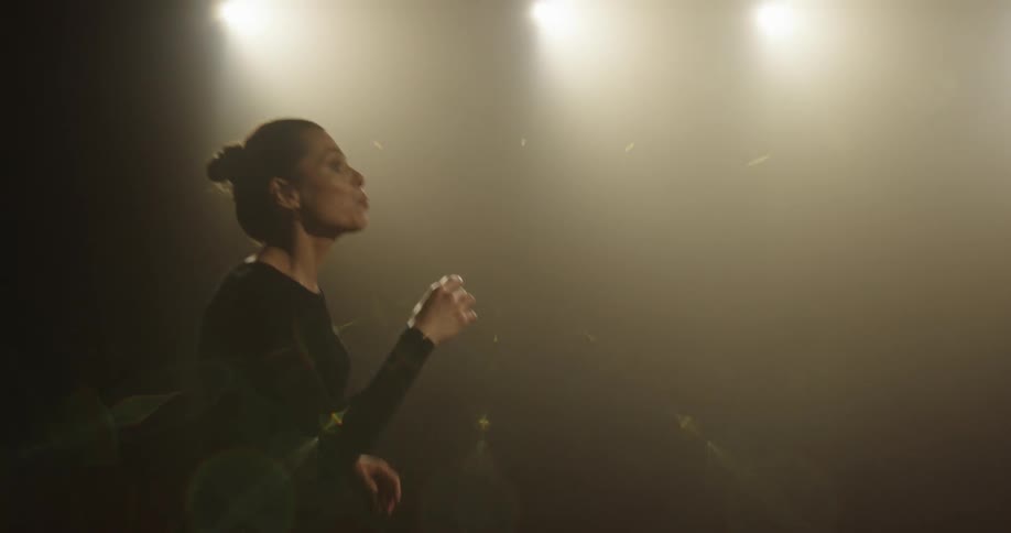 A woman sings while another woman is dancing to the music on a stage