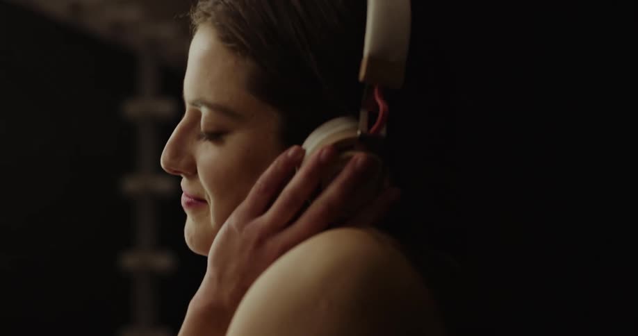 A woman wearing headphones smiles and sways to the music