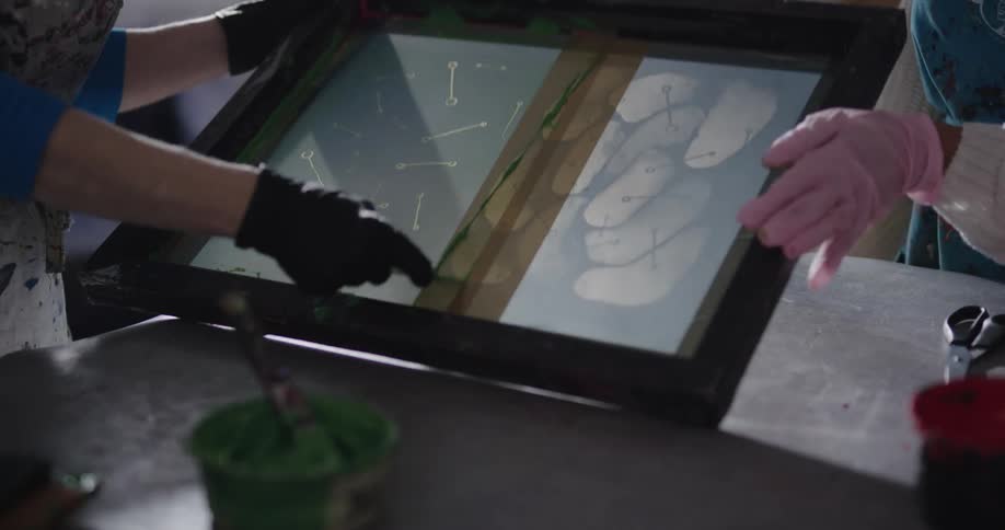 A painter putting paint from a cup onto a frame