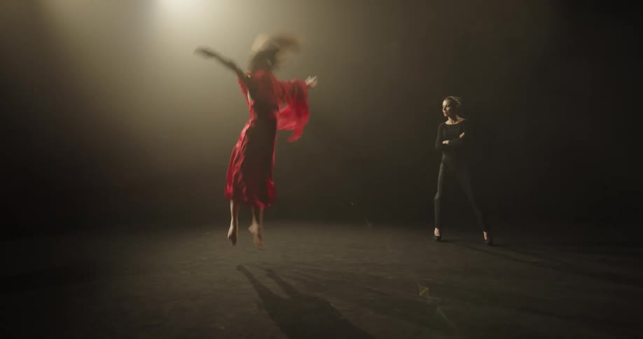 Dance instructor teaches female dancer in red dress techniques and dance moves on the stage