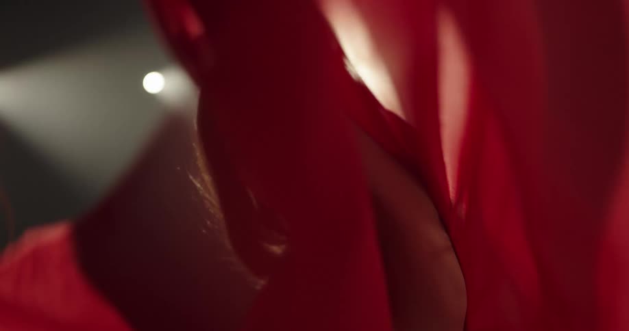 A woman in a room dancing with a wall and lights in the background