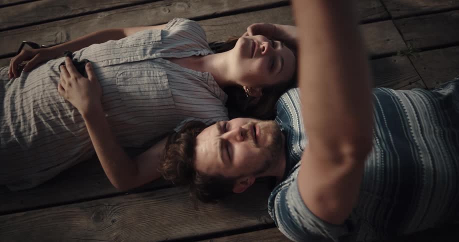 Couple lying on pier touches and kisses each other