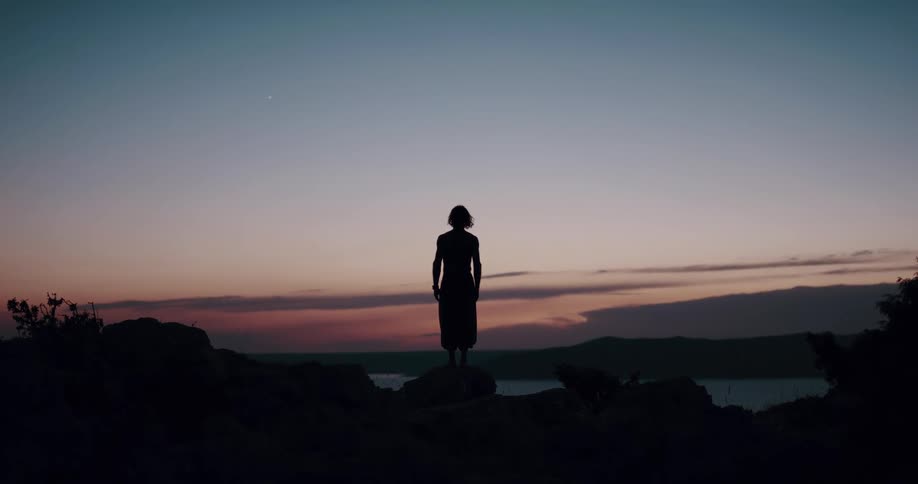 Woman standing and watching the horizon is silhouetted against the sky