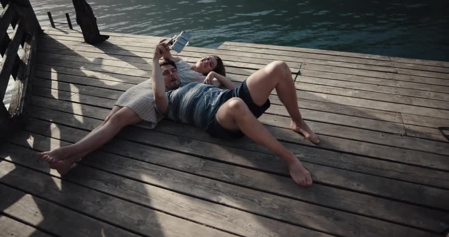 Two people that are dating on laying next to a lake