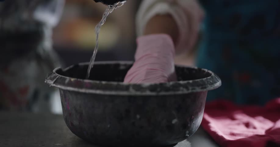Gloved hands reach into a bowl pull out sponges and squeeze the water out of them