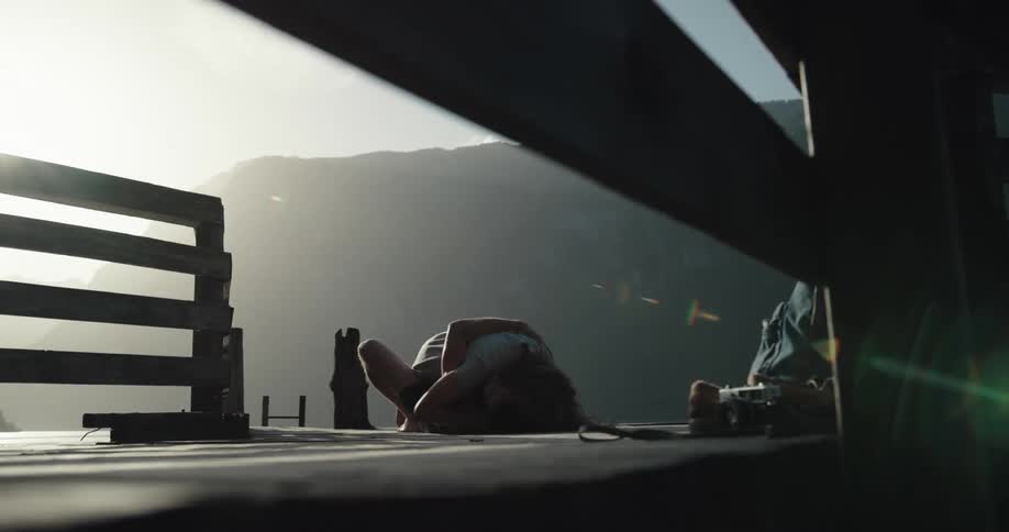 A couple play wrestle and kiss as they roll around on a pier near a canyon