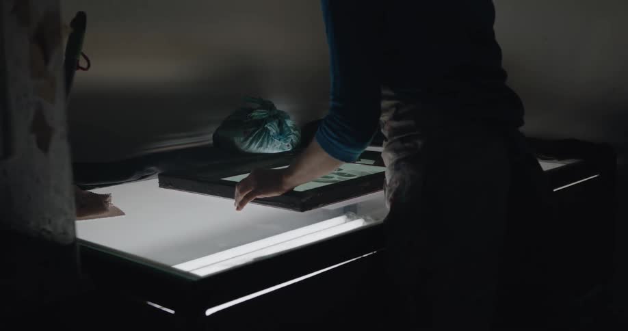 A woman is in a room at night and is looking at a picture frame