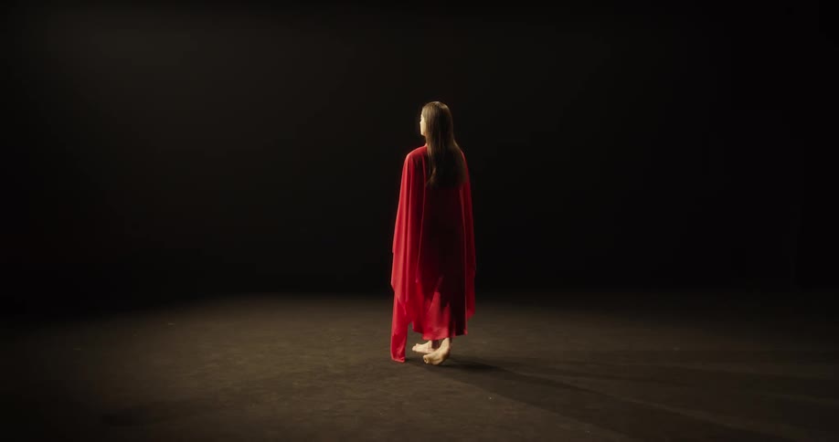 A woman is wearing a gown and walking across a stage