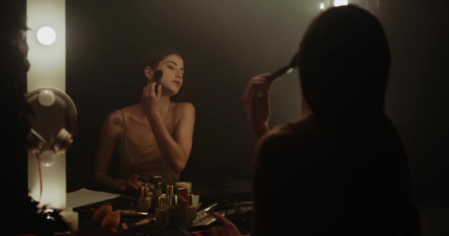 A woman is sitting in a chair and putting on makeup