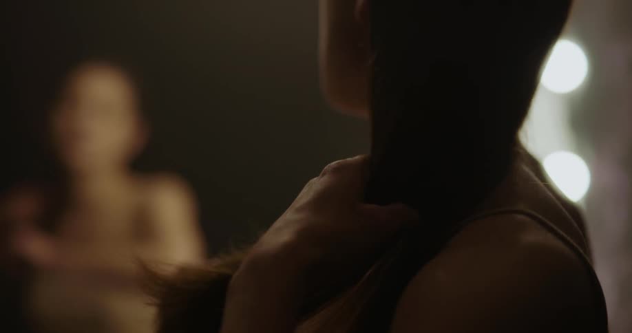 Female dancer looks in a mirror and combs her hair