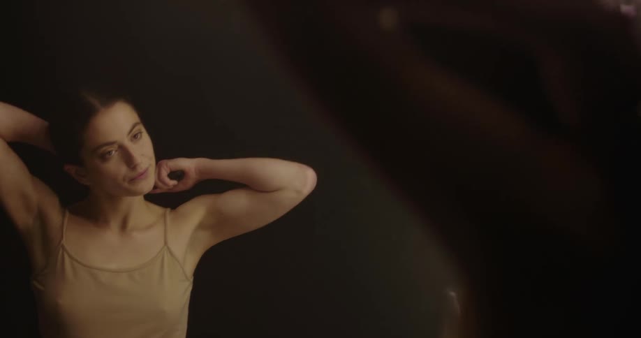 A woman brushes her hair in the mirror and twists it into a low bun
