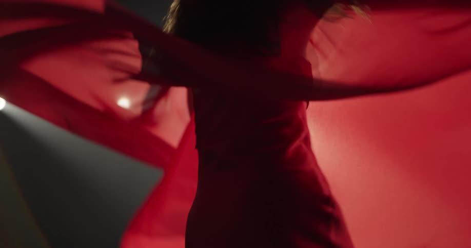 Dancer wearing red spins on stage under spot lights
