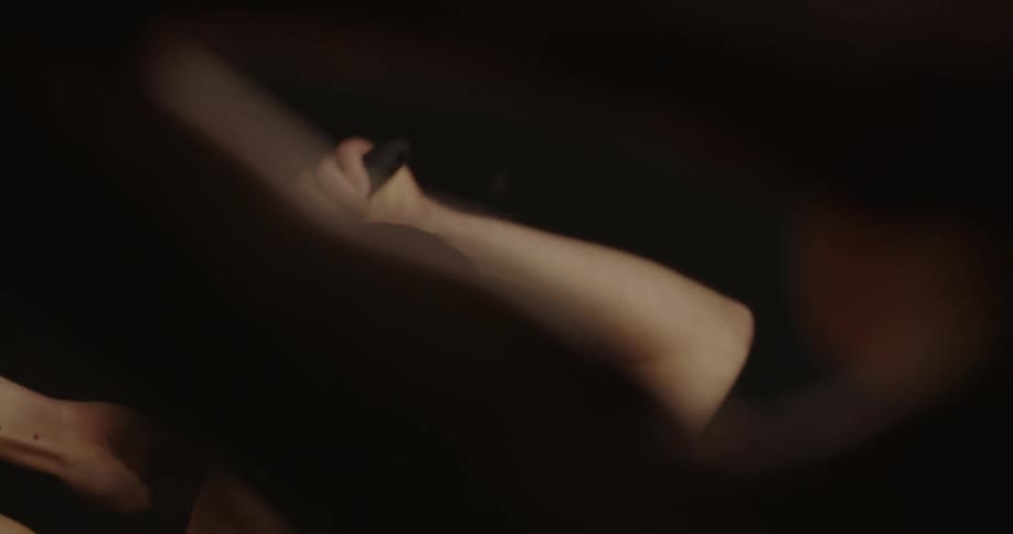 A woman is looking at herself in mirror as she brushes her hair