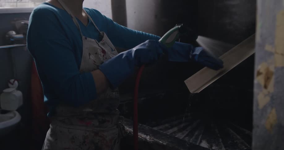 A woman is spraying off a piece of metal trim in a kitchen
