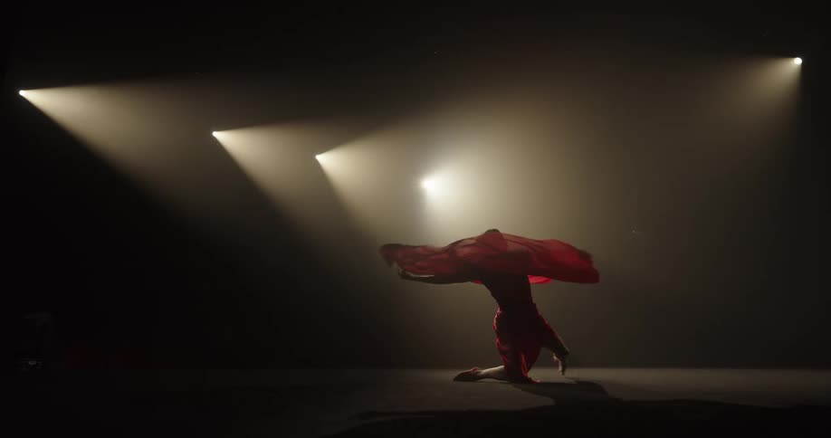 A young woman dances in a flowing red dress