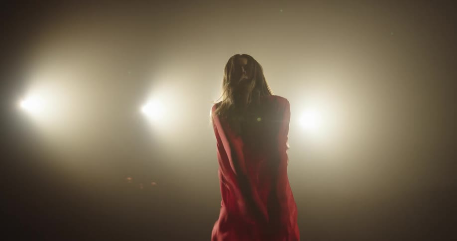 A woman is dancing on a stage and wearing a dress