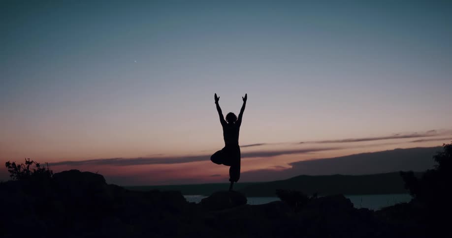 A woman holds a yoga pose on the shore