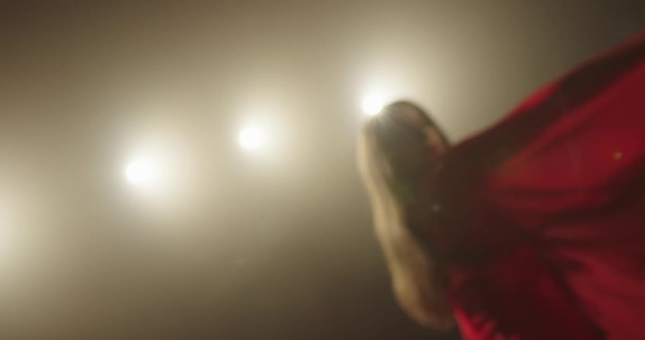 A woman in a room dancing with a wall and lights in the background
