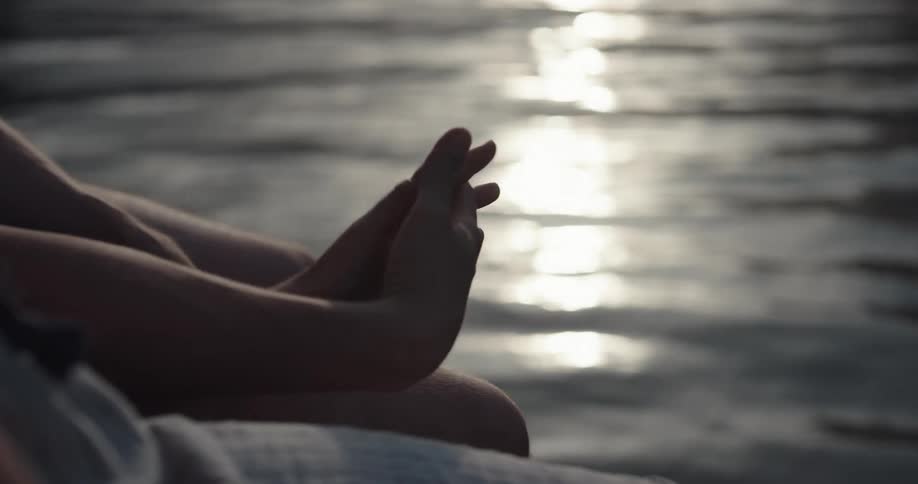 Couple sits on deck near water holding hands as rippling water stretching toward mountains on shore reflects light