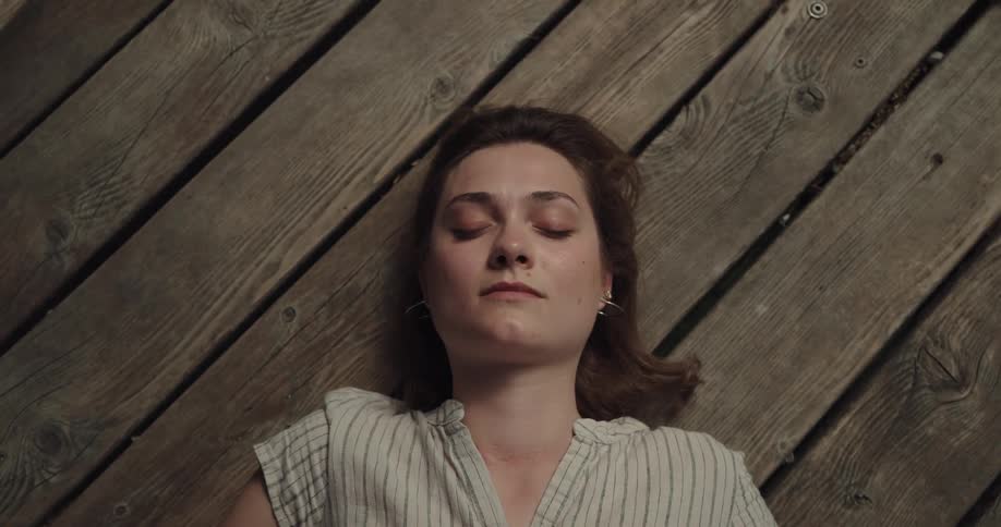 Wind blows through a womans hair as sleeps on a wooden pier