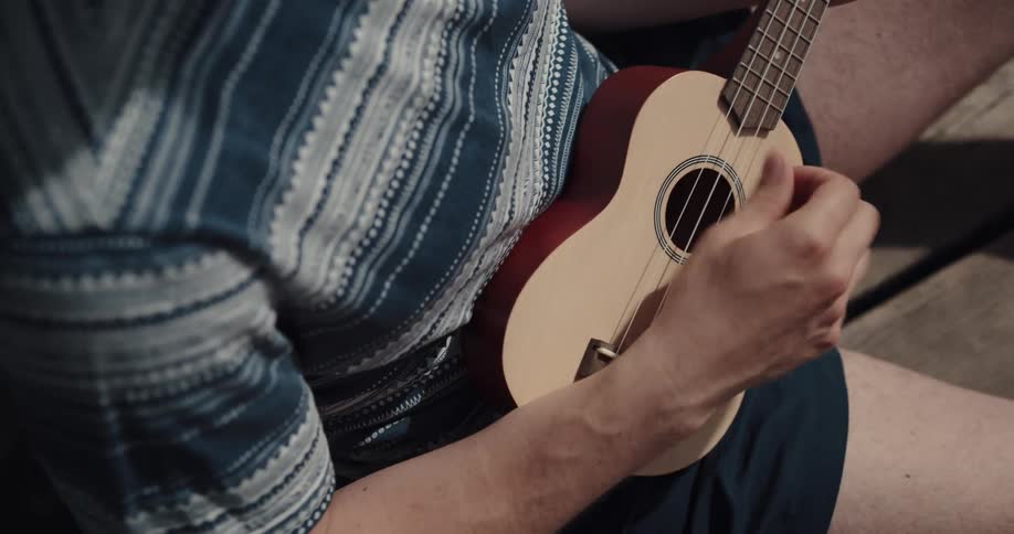 A person is standing on a wooden deck playing guitar