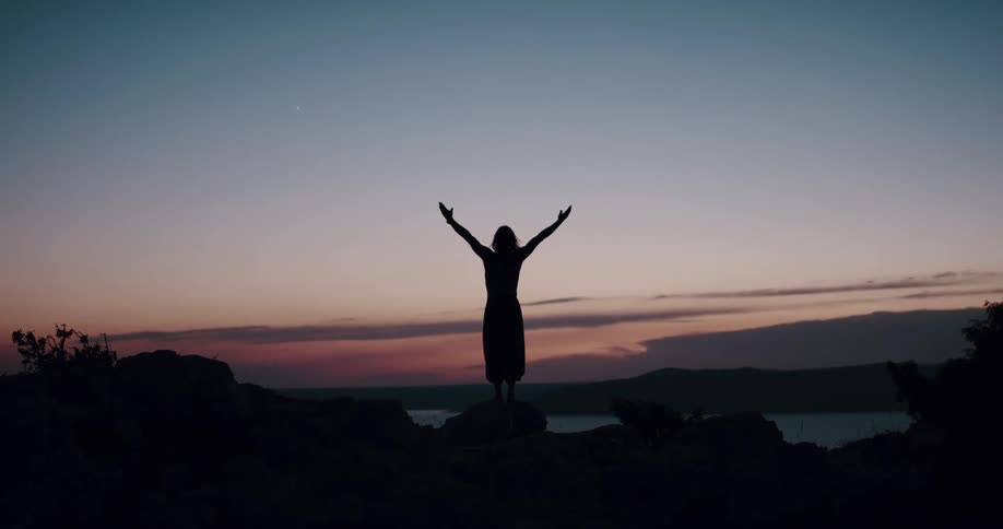 A man is stretching outdoors and watching the sunset