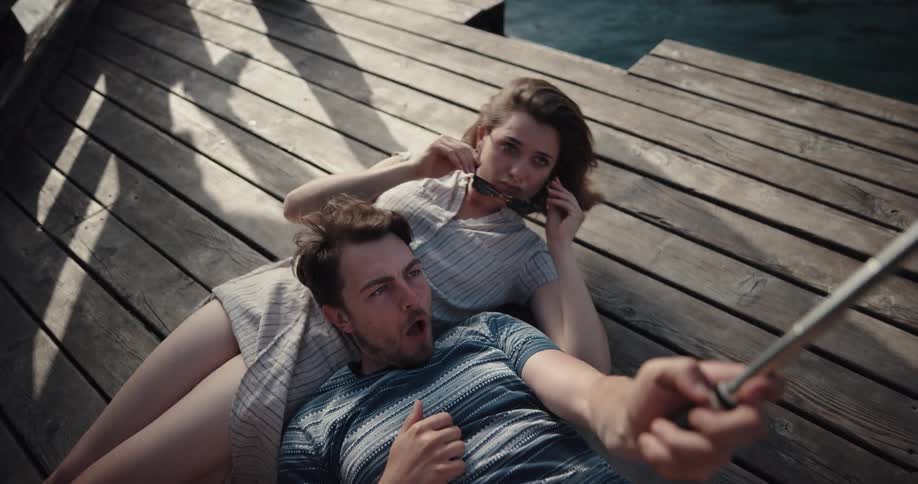 Boyfriend and girlfriend are laying down next to a lake
