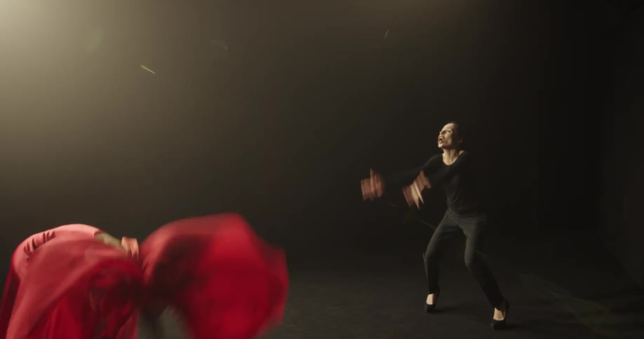 A woman coaches student on stage performing a modern dance