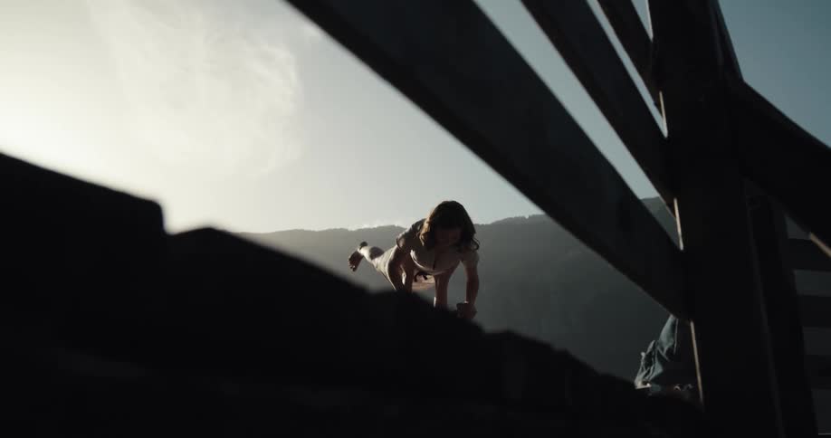 A man balancing a woman with his foot and hands on a dock with the sky and clouds in the background