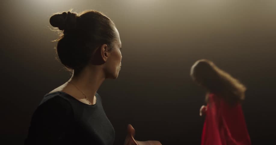 Dance instructor teaches female dancer wearing red dress techniques and dance moves on the stage